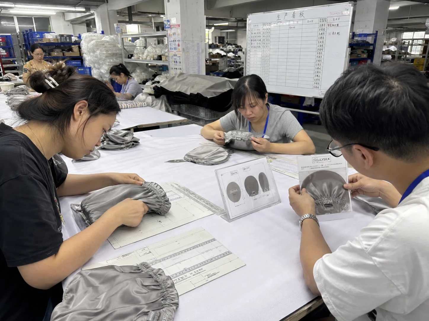 In-process quality check during sewing, with staff inspecting seams and logo placement against order sheets to support consistent quality for B2B