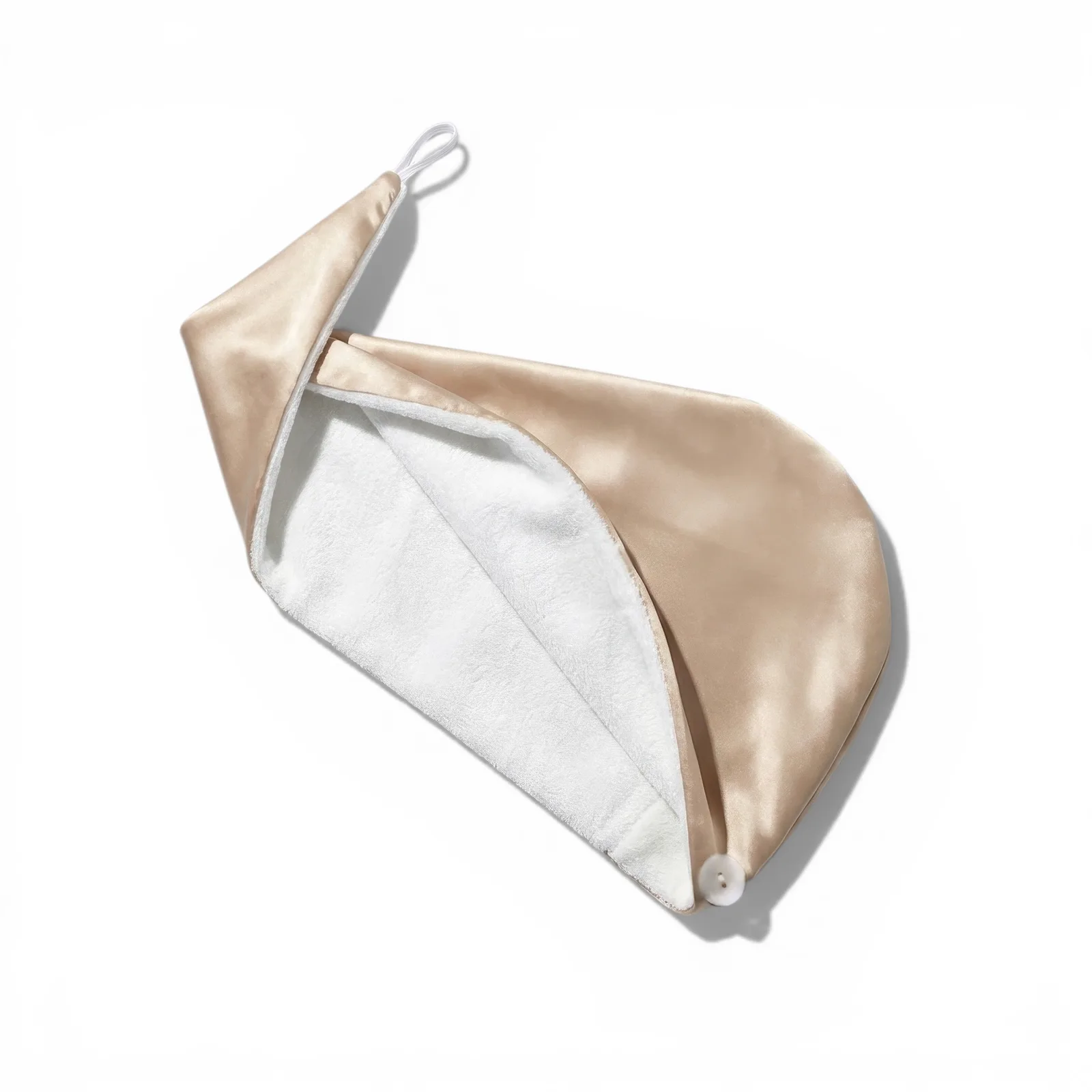 Detail view of custom silk hair towel wrap with champagne outer finish, soft inner lining, button loop closure, and contrast edging for private label