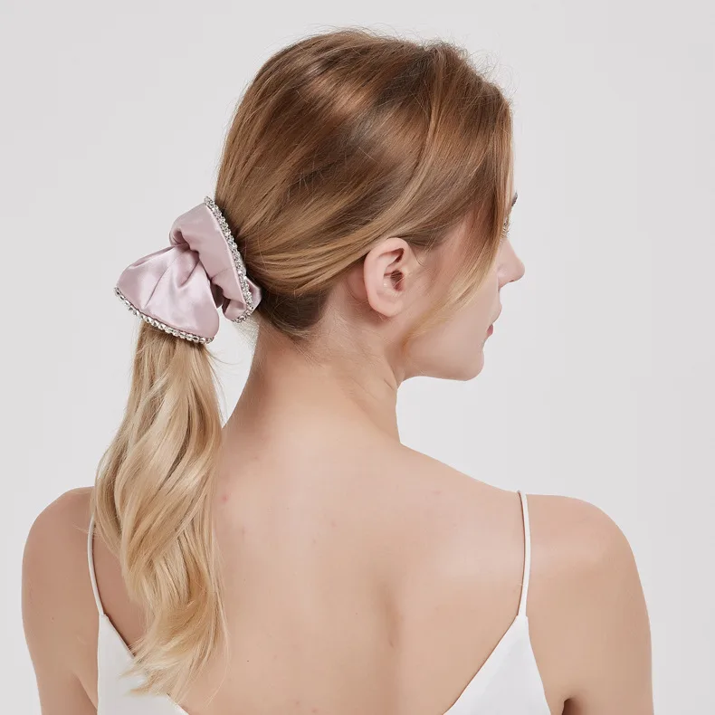 Dusty pink bow scrunchie with rhinestone trim worn in a ponytail for private label hair accessory and gift set programs