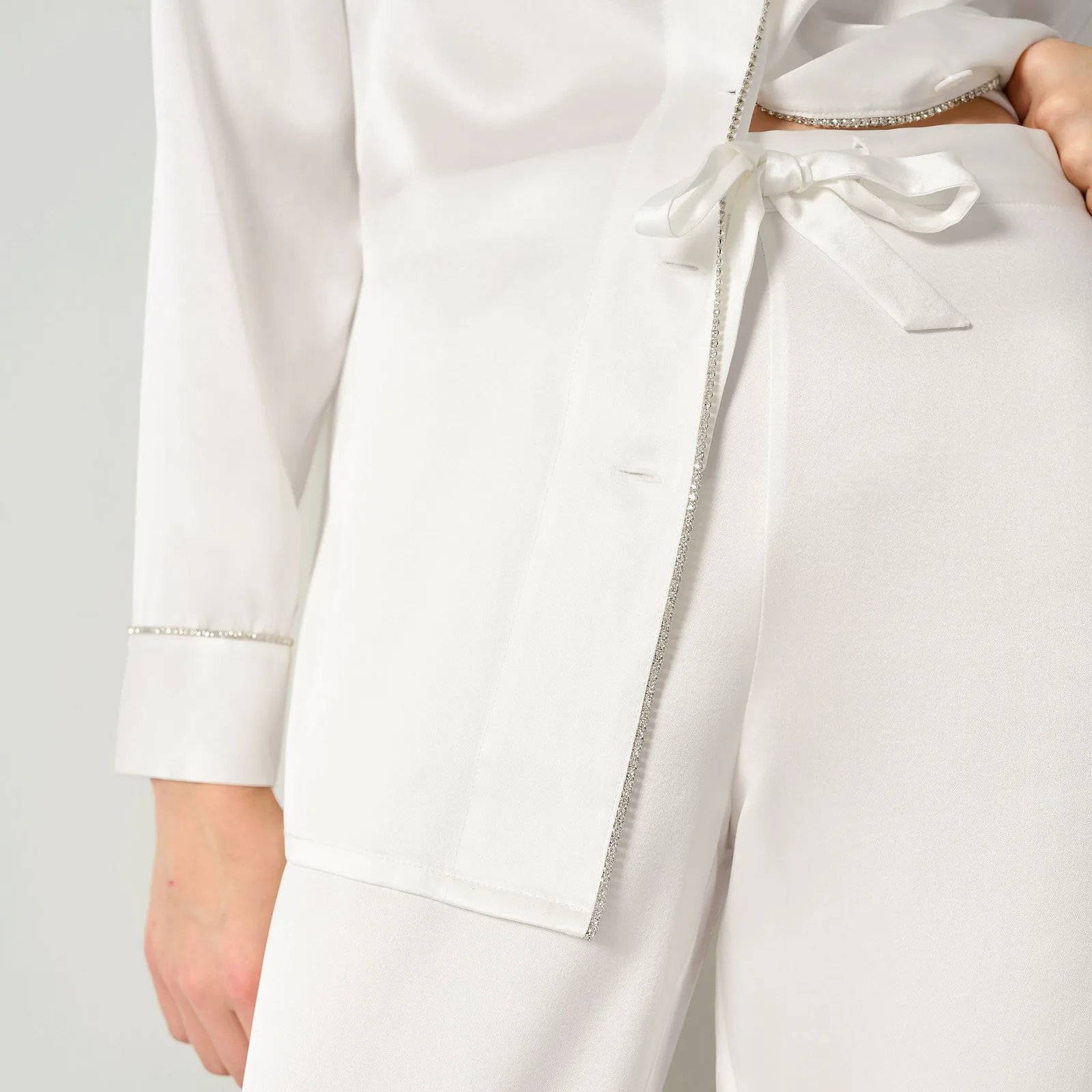 Detail view of white satin-finish sleepwear with crystal-style trim and tie detail for private label gift set customization