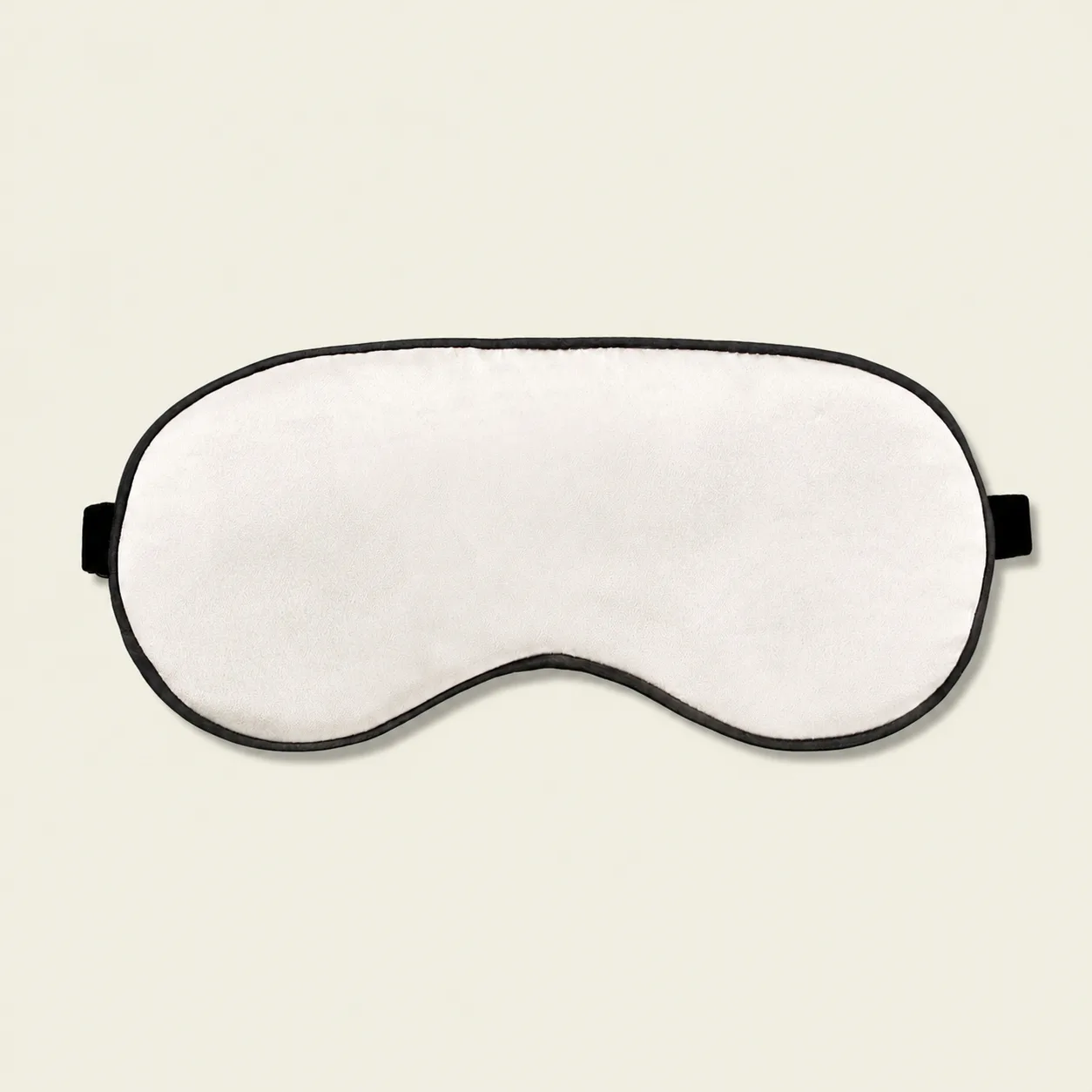 Detail view of a cream sleep mask with black piping and side label for custom private label gift sets