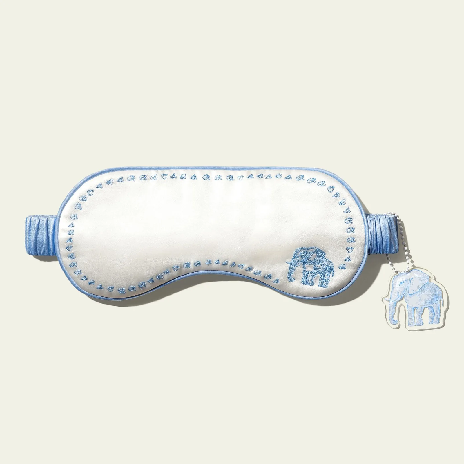 Custom silk sleep mask style with blue embroidered elephant motif and matching tag for private label gift set programs