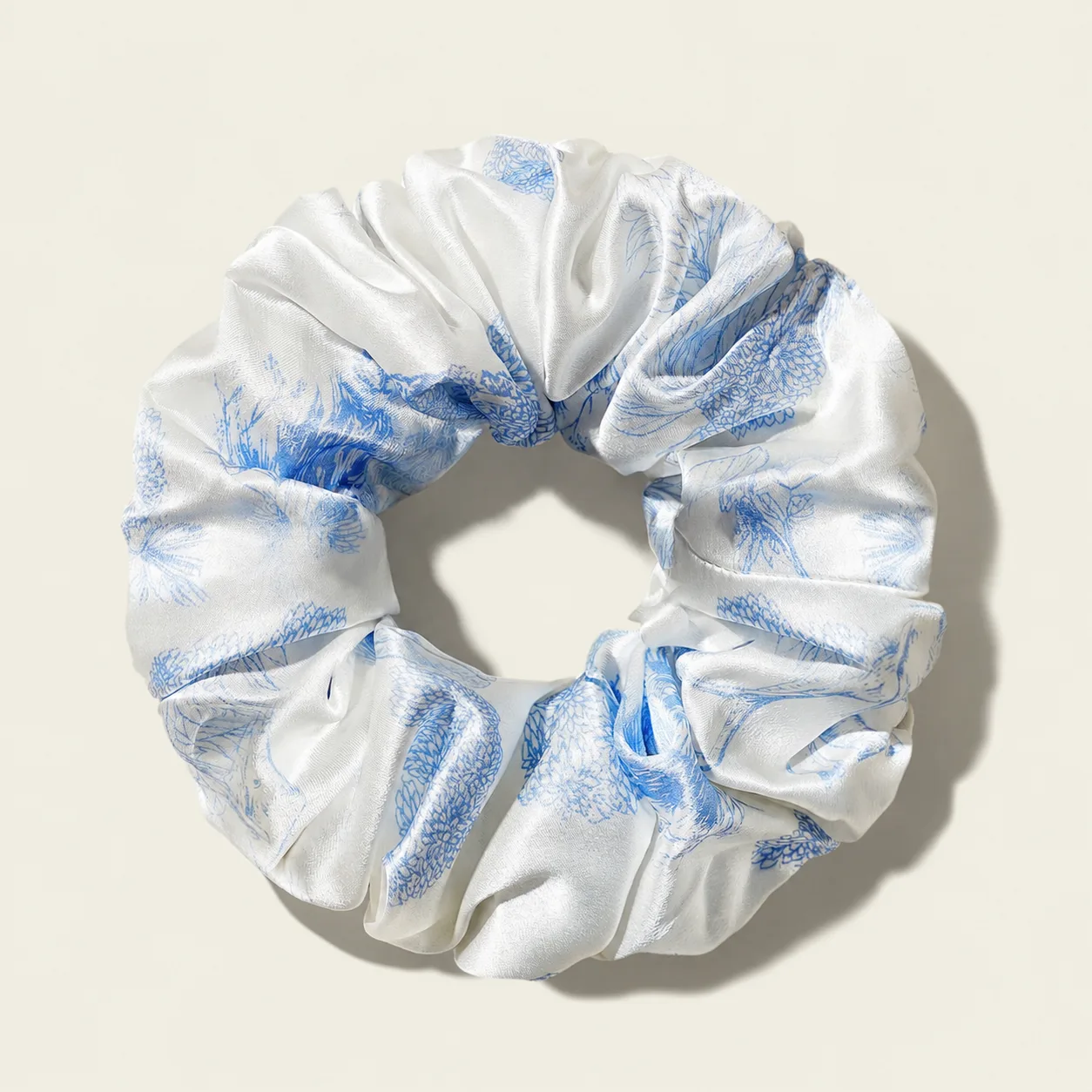 Detail view of a white and blue printed scrunchie with logo label for private label beauty, spa, and custom silk gift set programs