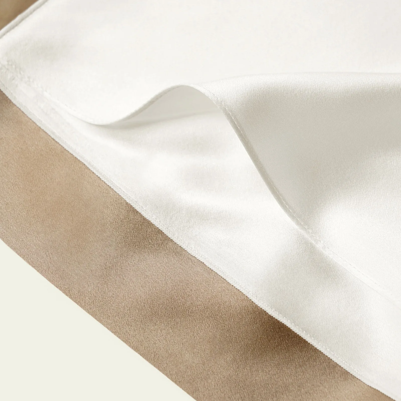 Close-up detail of a white custom silk pillowcase with stitched edge, showing finish quality for private label hair and sleep care lines