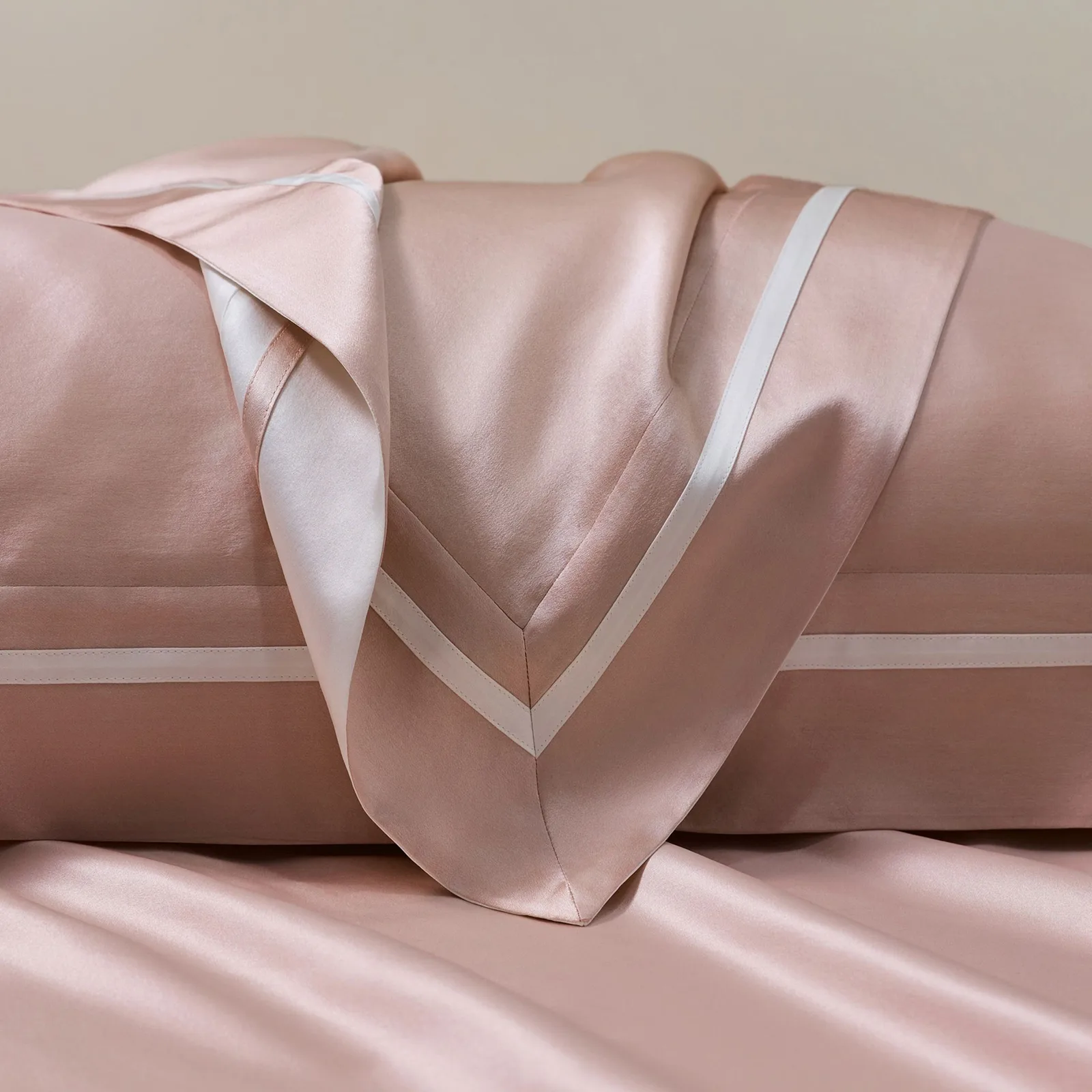 Detail view of blush pink custom silk bedding with contrast piping and seam finishing for private label bedding collections