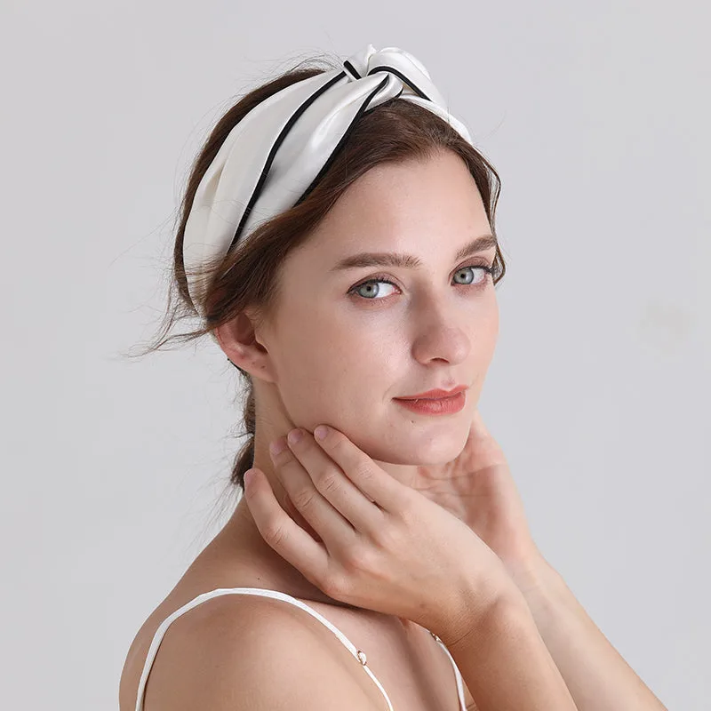 White knotted custom silk headband with black trim shown in a lifestyle model image for private label beauty and hair accessory brands