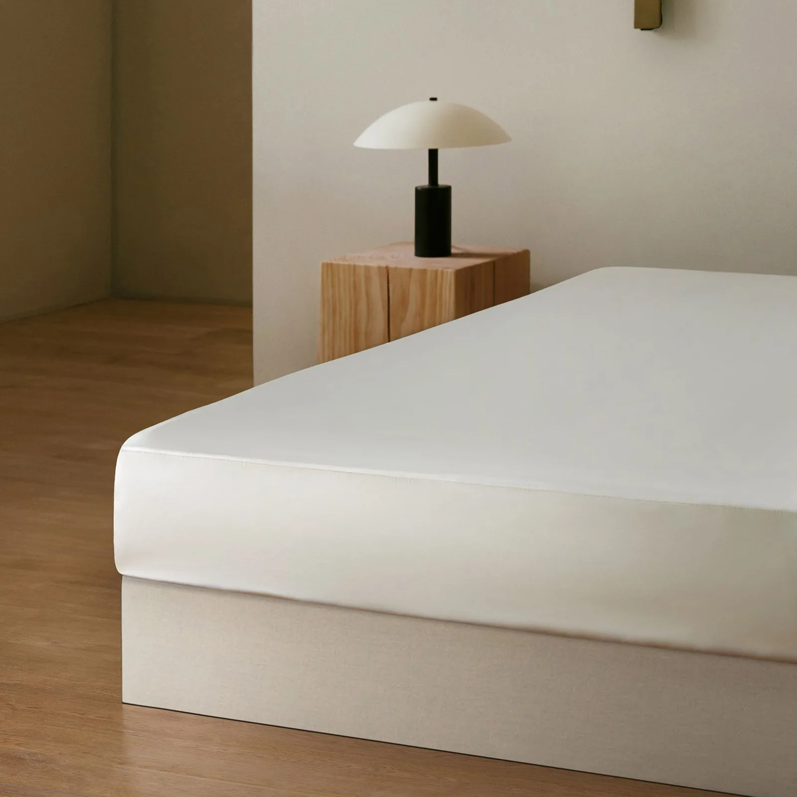 Detail view of white custom silk bedding sheet style on a minimalist bed for private label hospitality and retail programs
