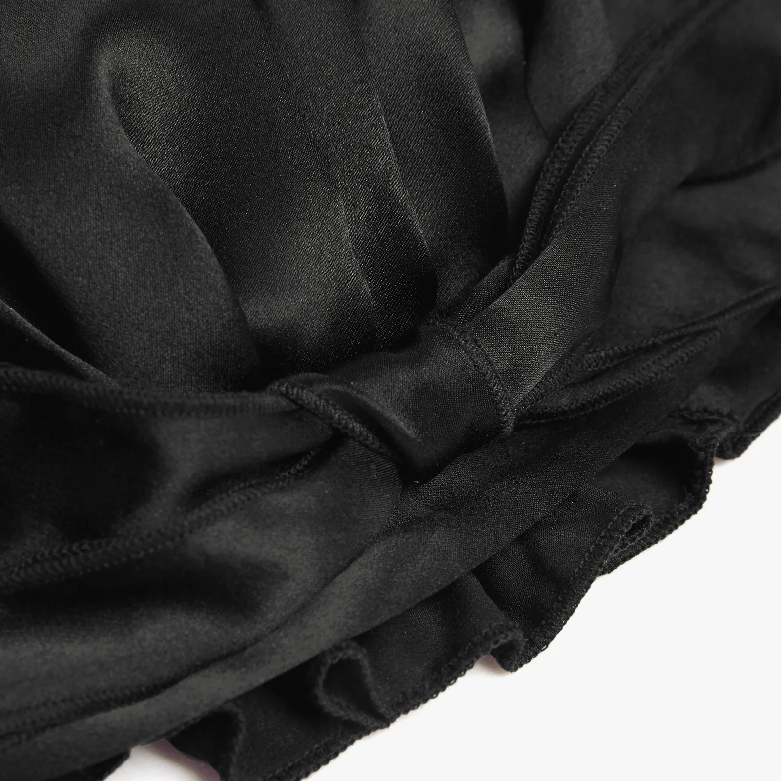 Detail view of black custom silk sleep cap with smooth fabric, gathered panels, and stitched edge for private label hair care brands