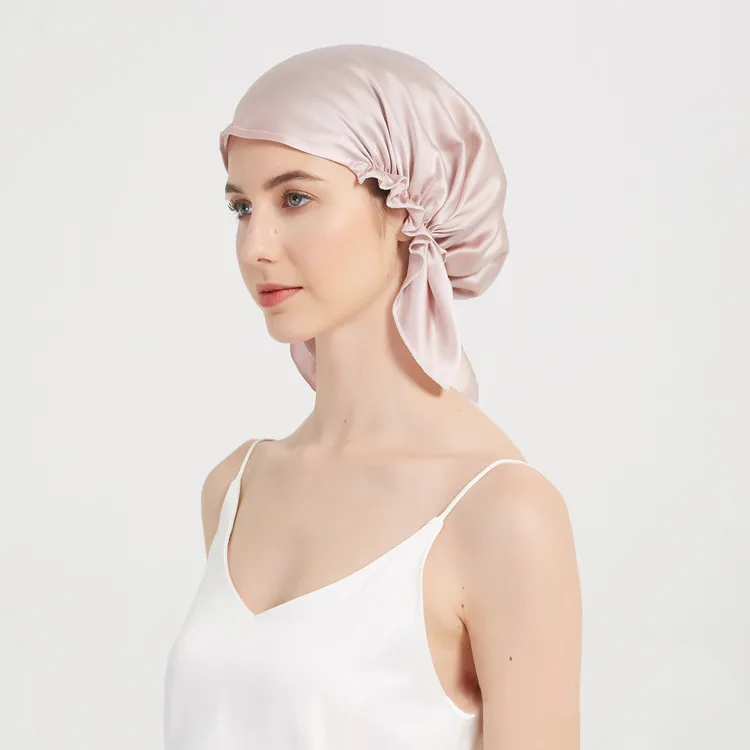 Detail view of a blush pink custom silk sleep cap with tie-back fit for private label hair care and beauty brand collections