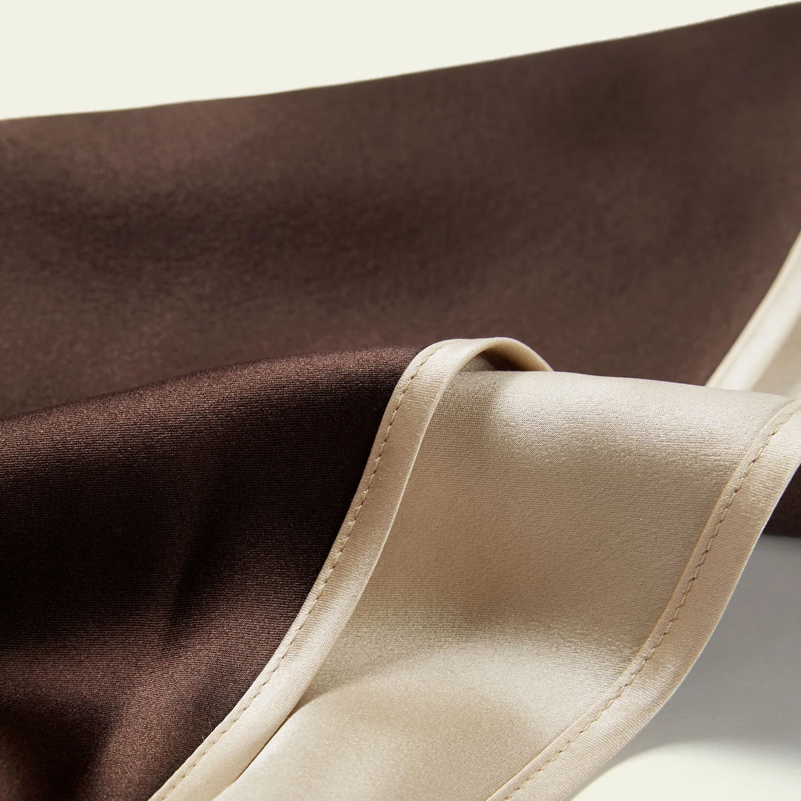 Detail of custom silk sleep cap with two-tone fabric and stitched edge for private label hair care brands