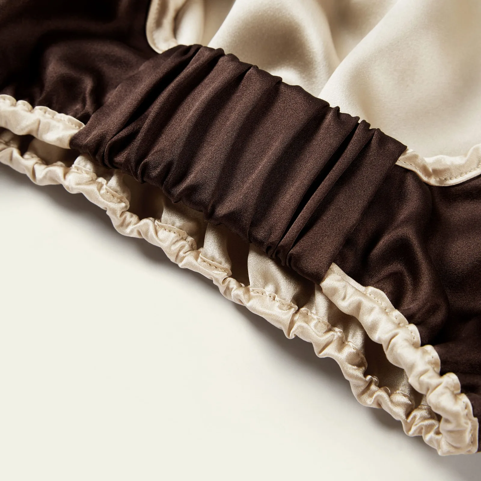 Detail view of two-tone custom silk sleep cap with ruched elastic edge for private label hair care brands