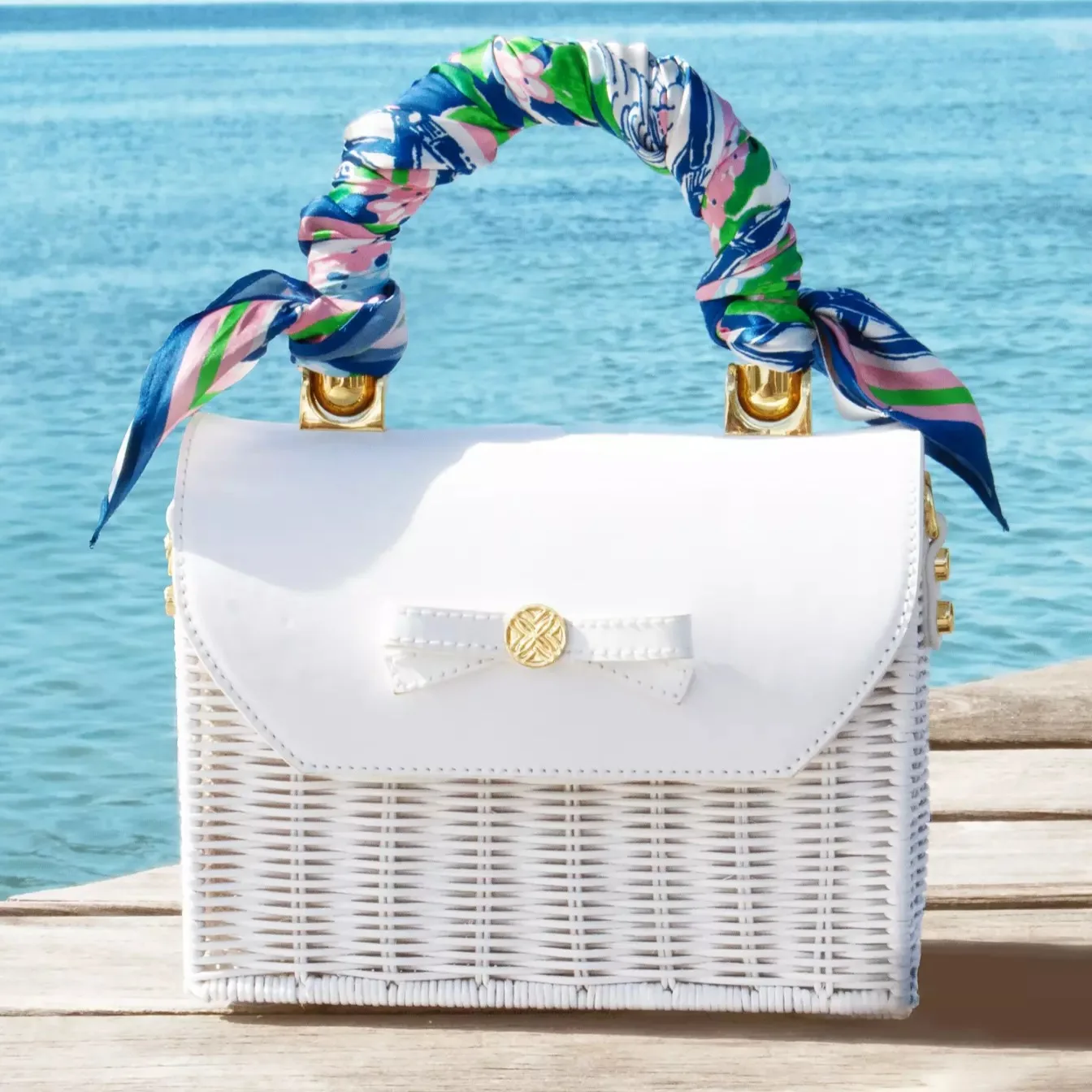 Printed custom silk scarf tied on a handbag handle, showing resort-style color placement for private label accessory collections