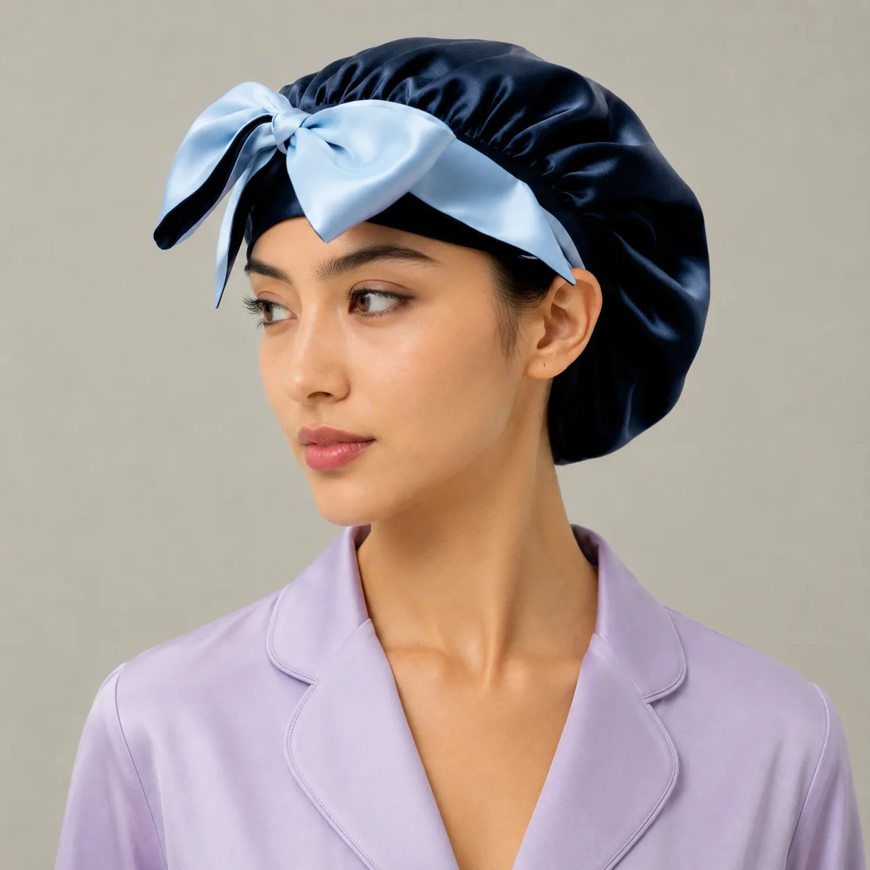 Detail view of custom silk sleep cap style with navy crown and light blue bow band for private label hair care brands