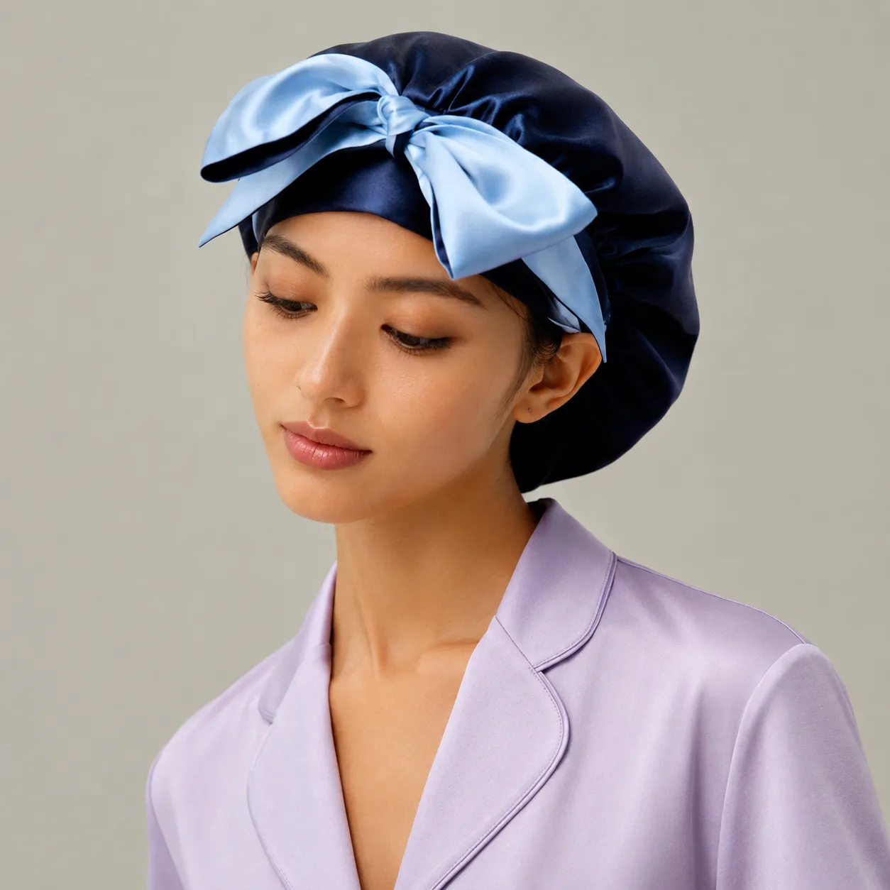Custom silk sleep cap with navy body and light blue bow detail for private label hair care and beauty brand collections