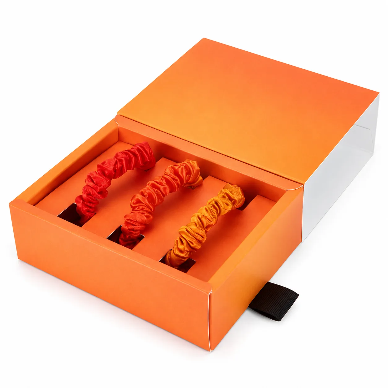 Custom silk scrunchies in coordinated warm colors presented in an orange gift box for private label hair accessory and gift set brands