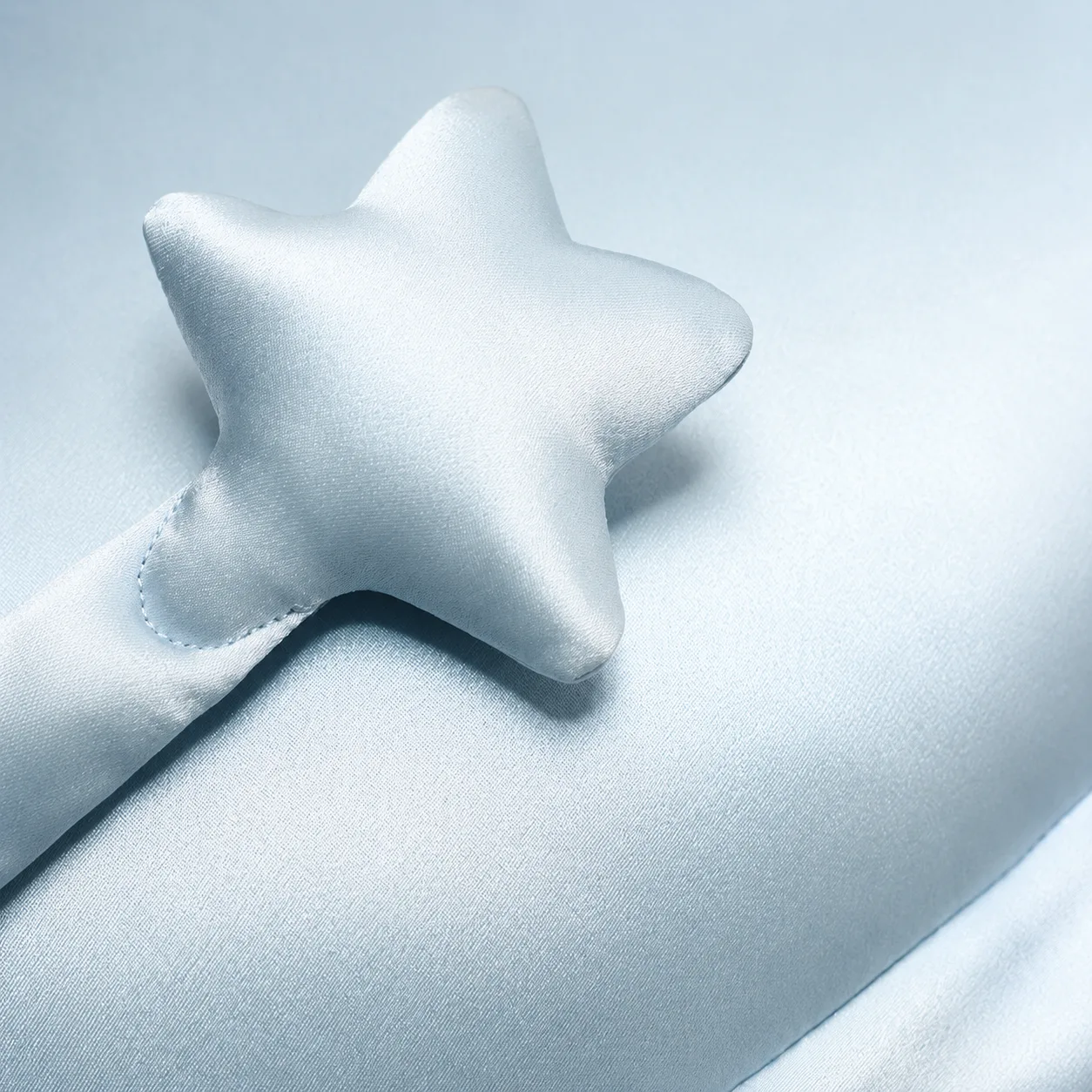 Detail view of a kids silk pillow with a padded star-shaped accent, rounded points, and stitched edge construction for private label comfort review