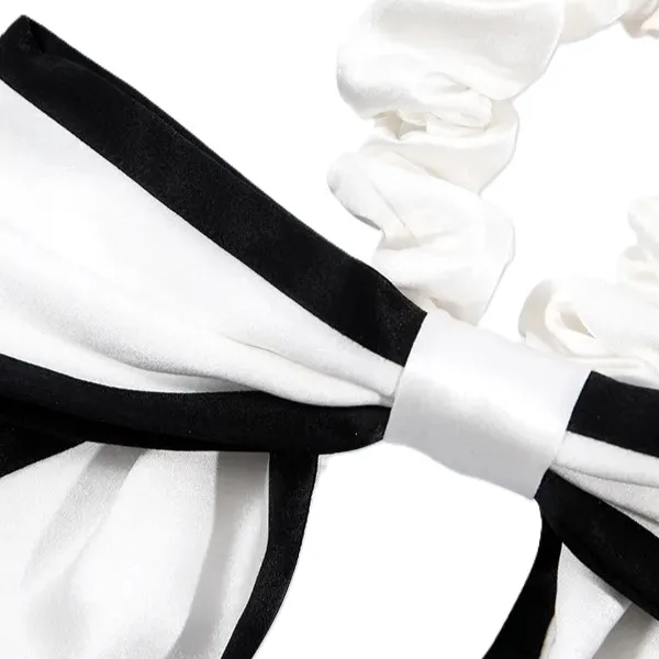 Detail view of custom silk bow scrunchie showing wrapped center band, long bow tails, and finished edge construction for private label hair accessory
