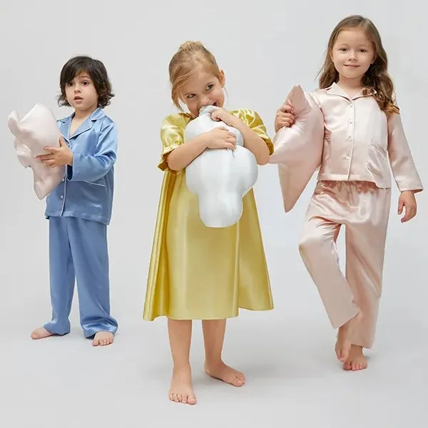 Kids holding shaped silk decorative pillows with plush padding and rounded stitched edges for private label children’s collections