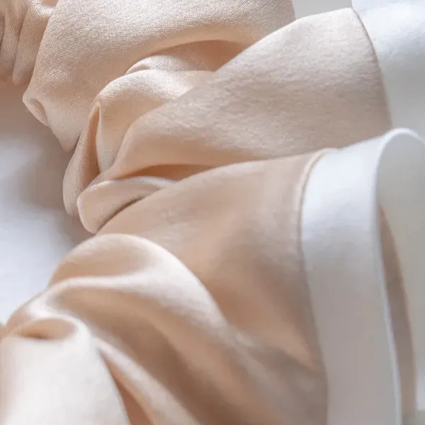 Close-up of two-tone silk scrunchie fabric showing soft drape, gentle sheen and hand-feel considerations for private label hair accessory collections