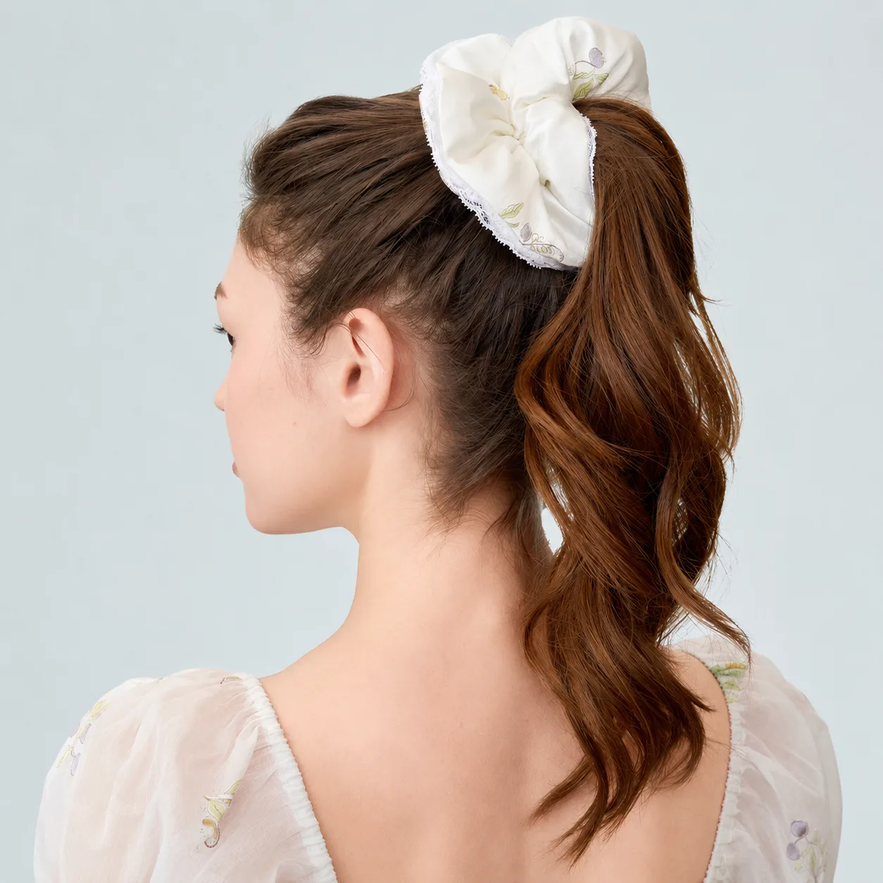 Detail view of a custom silk scrunchie with gathered padded construction, finished ruffle edge, and elastic band fit for comfortable ponytail hold in