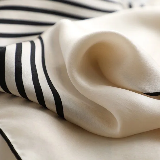 Detail view showcasing the modern geometric construction of a custom 90cm square silk scarf with precision edge finishing, highlighting its soft drape
