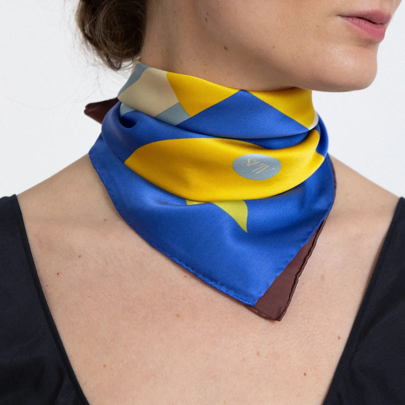 Detail view of a custom paisley print silk square scarf with a classic triangular shape, featuring tailored edges and a snug fit around the neck