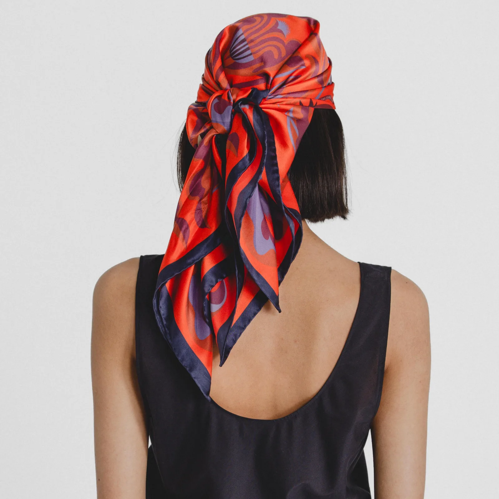 Detail view of a custom silk scarf featuring a colorful geometric design, showcasing its lightweight, elegant structure and versatility in styling for