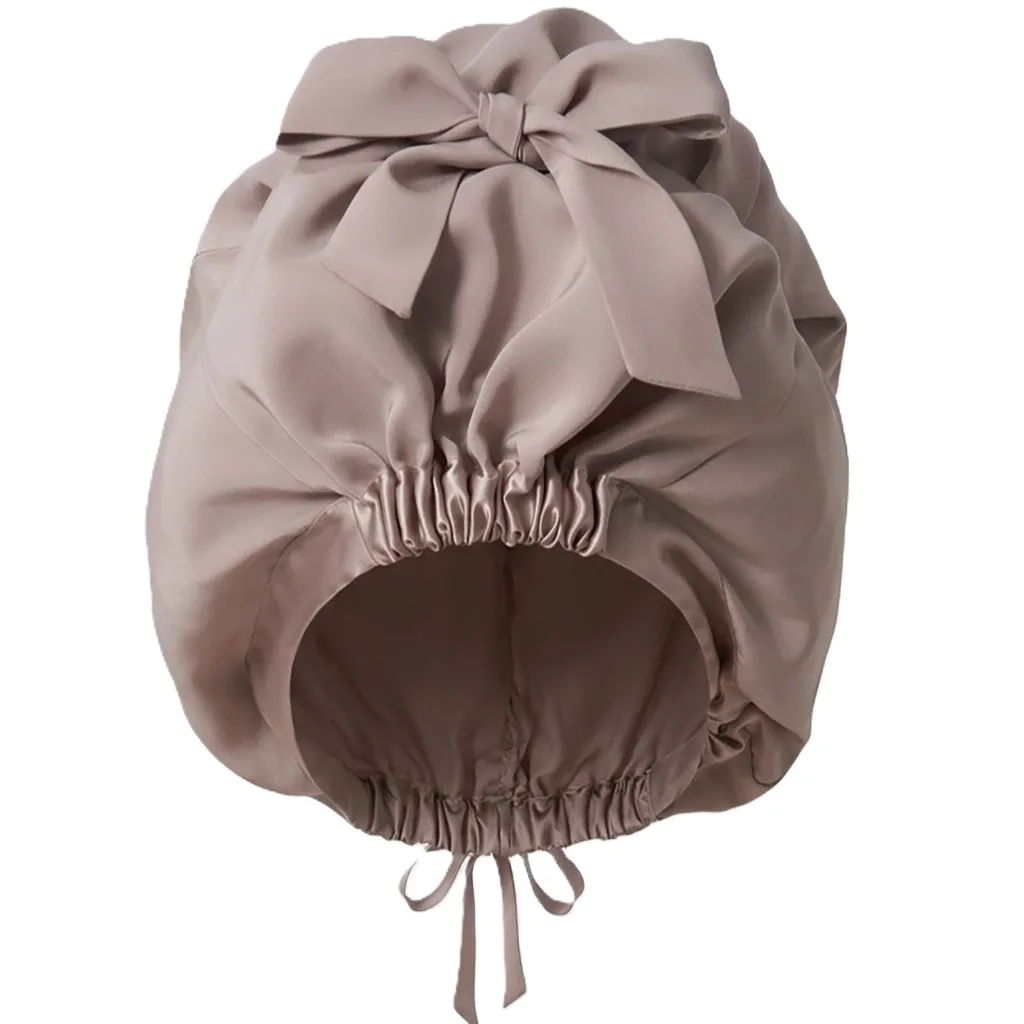 Detail view showcasing the construction and fit of a custom silk sleep cap, featuring an elastic band for secure wear and a refined bow accent for